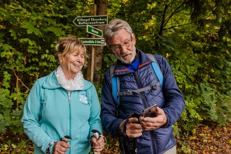 Das Bild zeigt ein älteres Ehepaar in eine Wanderkarte schauent vor dem Wegweiser des Lutherwegs.