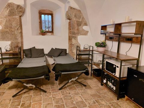 Zimmer in der Elisabethkapelle Grimma mit zwei Feldbetten in einem hellen, schlicht eingerichteten Raum, geeignet für Übernachtungsgäste.