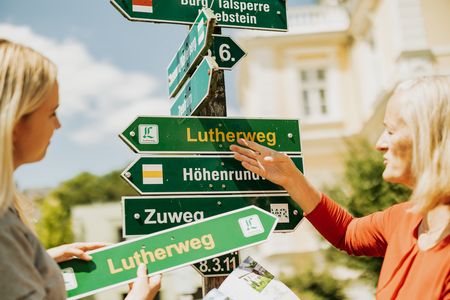 Zwei Wegemanagerinnen zeigen den Wegweiser des Lutherweg Sachsens.