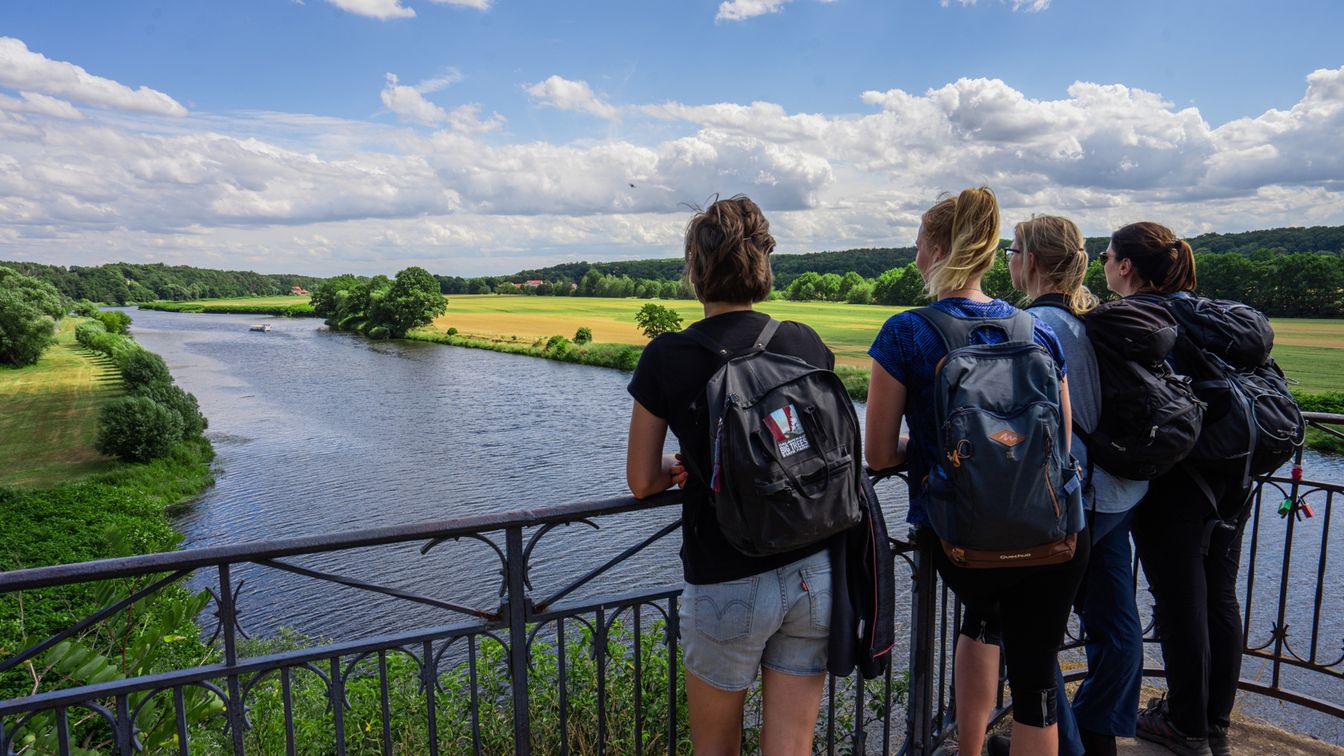 Das Bild zeigt eine Gruppe von Wanderen, wie sie vom Aussichtspunkt auf die Mulde schauen und die Aussicht genießen.