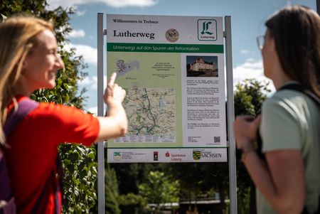 Zwei Wanderinnen stehen vor einer Infotafel des Lutherwegs 