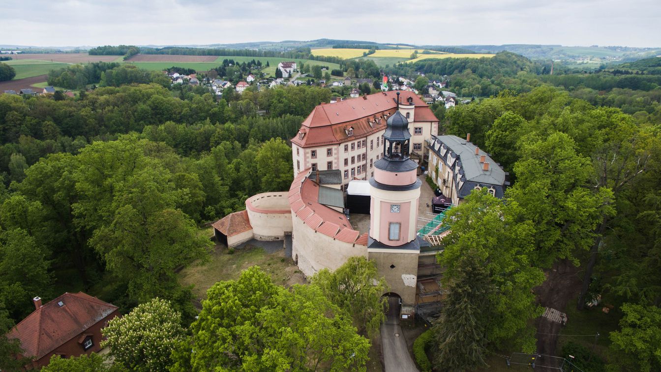 Eine Drohnenaufnahme von Schloss Wolkenburg inmitten von einem Waldgebiet.