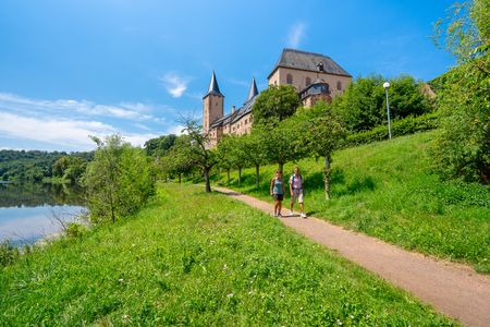 Das Bild zeigt zwei Wanderer die vor Schloss Rochlitz entlang der Mulde unterwegs sind.