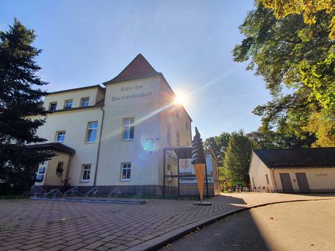 Haupthaus des Ritterguts Dornreichenbach mit angrenzendem Kiosk, umgeben von Grünflächen und Bäumen bei sonnigem Wetter.