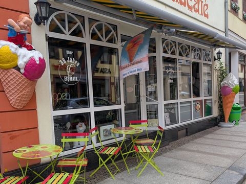 Blick auf das Cafe Eismaik, mit gelben Stühlen vor dem Laden. 