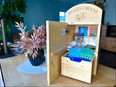 Das Bild zeigt einen geöffneten Pilgerschrank aus Holz mit Stempel und Hilfsmitteln.